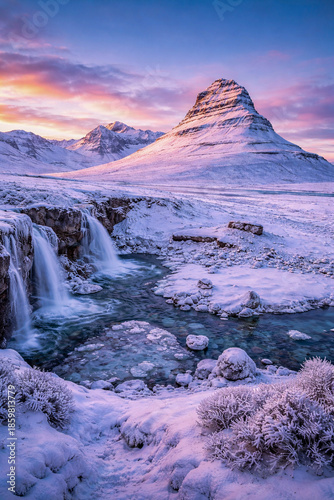 Dreamy Icelandic Winter Landscape with Snow Covered Mountains, Frozen Waterfall and Turquoise River at Sunrise