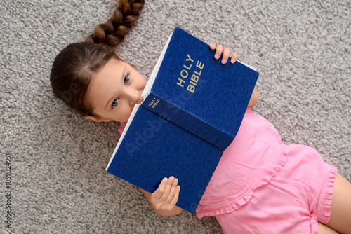 Cute little girl reading Bi...
