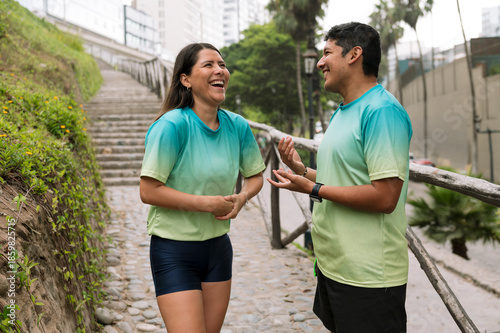 Multiracial, athletic couple smiling after training outdoors on a sunny morning