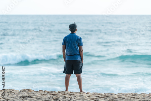 Foto Man contemplating ocean vista from sandy beach
