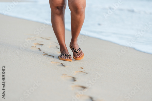 Woman walking creating footprints on beach sand