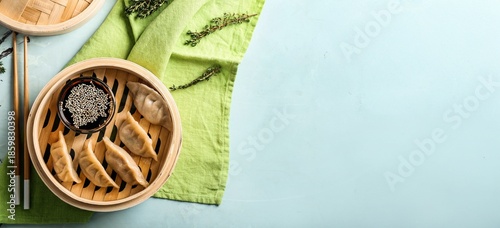 Tableau sur toile Bamboo steamer with tasty gyoza on light blue background with space for text, to