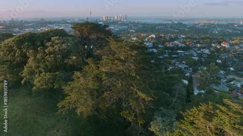Aerial view of Auckland, New Zealand, showing the city skyline and residential areas. The scene captures the urban landscape and the natural beauty of the region.