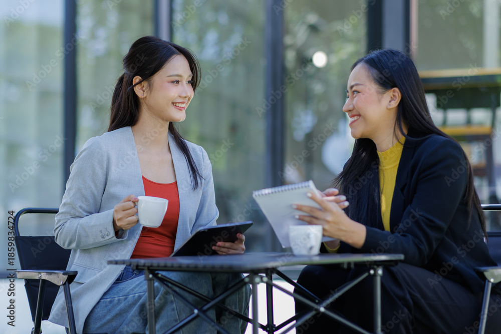 Obraz premium Two business working together using digital tablet pc and talking about a business project. Small creative diversity team of females executives meeting work in office. 