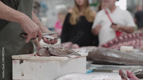 Local fish market showcases fresh seafood being prepared by skilled workers while shoppers browse various catches and enjoy the lively atmosphere.