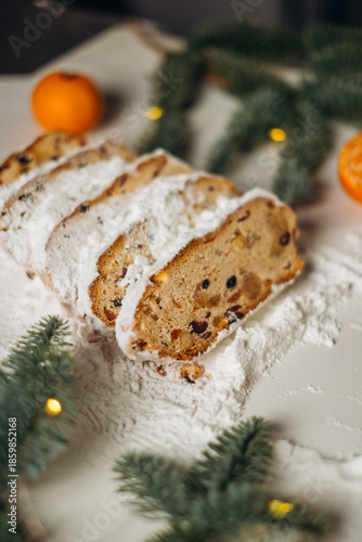 Traditional Christmas stollen, sliced and dusted with powdered sugar, filled with candied fruit, raisins, and nuts. A festive atmosphere, a warm and cozy winter mood.