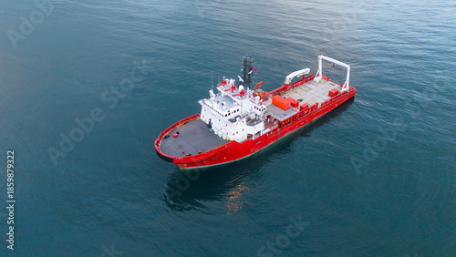 High angle drone view of a red research ship navigating through deep blue waters highlighting the bridge and deck layout suitable for industrial maritime exploration projects