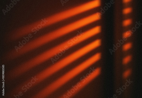 Fotografie Abstract warm red light patterns cast through window blinds at dusk, forming diagonal stripes and a moody cinematic atmosphere ideal for creative projects and striking backgrounds