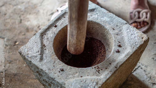 Grinding coffee in the traditional way using a stove made of stone (Indonesians call it lumpang)