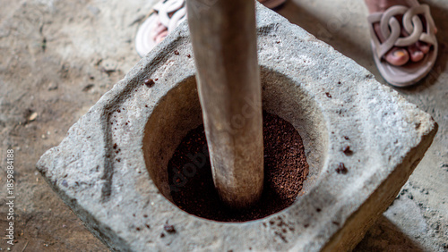 Grinding coffee in the traditional way using a stove made of stone (Indonesians call it lumpang)