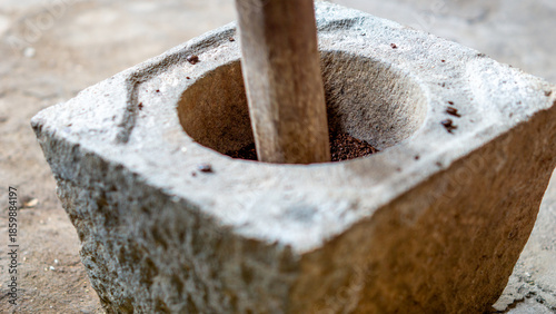 Grinding coffee in the traditional way using a stove made of stone (Indonesians call it lumpang)