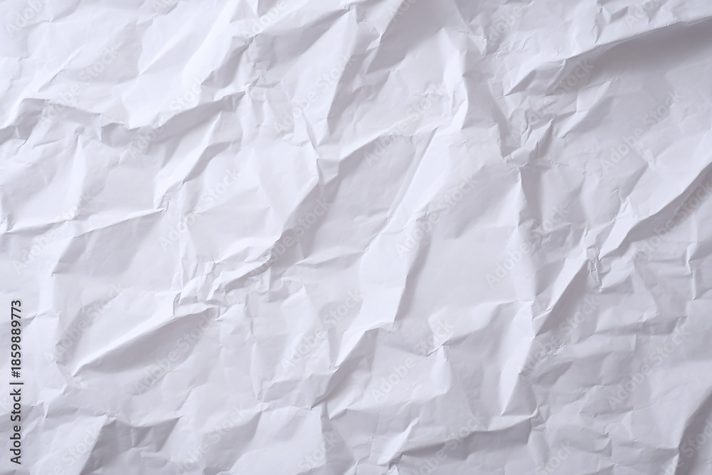 Obraz premium Crumpled white paper texture with uneven folds and creases.