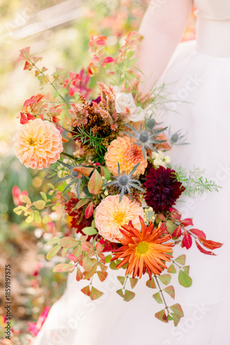 A bride holding a floral bouquet with autumn colors