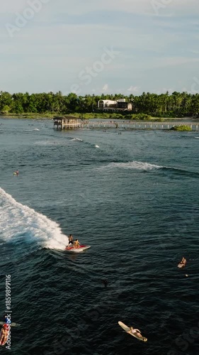 Surfers catching waves close to the long wooden pier. Cloud 9 Surfing Area. Siargao, Philippines.