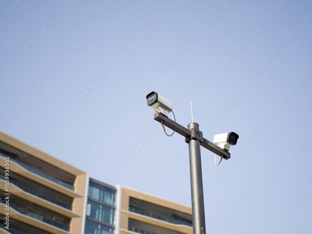 Obraz premium Dual security cameras on pole against apartment