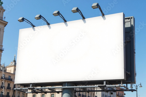 A mockup of a blank white billboard framed by a modern building facade under a clear blue sky in madrid city,ideal for advertising. 3d rendering.