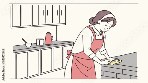 A woman in an apron is cleaning the kitchen counter with a yellow cloth.