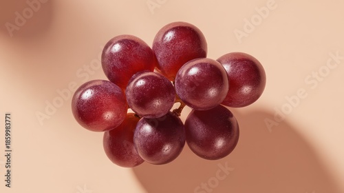 A bunch of grapes arranged neatly on a seamless matte background, directional lighting creating crisp shadows. Glossy textures reflect