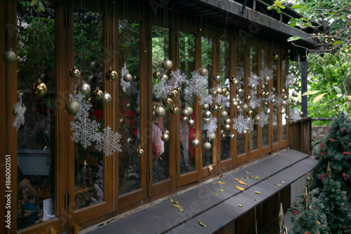 Festive golden ornaments and snowflake decorations hang elegantly on wooden-framed windows, creating a cozy holiday ambiance