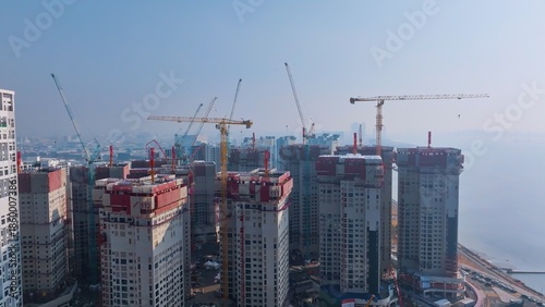 a large-scale urban construction site with multiple high-rise buildings and tower cranes, signifying rapid city expansion and modern architectural progress.