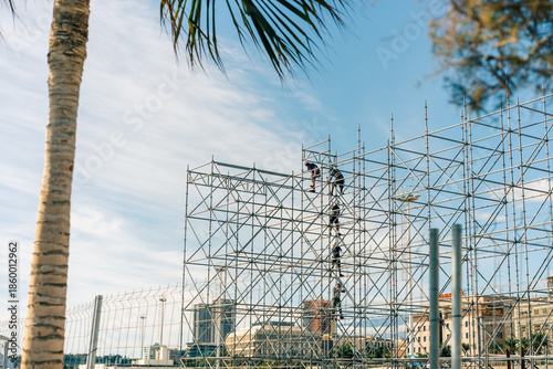  Scaffolding at a construction site with workers against a clear blue sky.