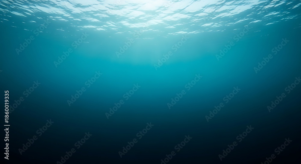 Obraz premium Underwater view looking up towards the sunlit surface, with light rays penetrating the deep blue ocean water