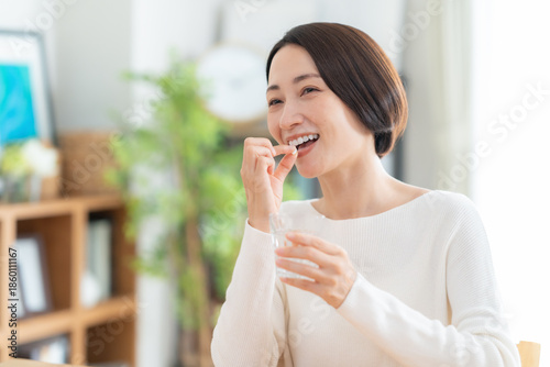 Photos リビングでサプリメントを飲むミドルの女性