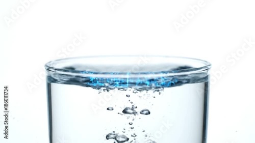 Close-up of a clear glass of water with rising bubbles against a white background