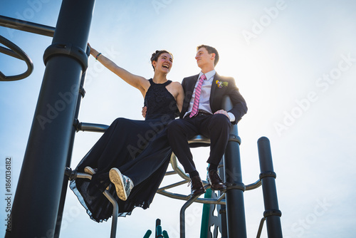 Принти на полотні Teen couple in formal clothing smile atop a playground structure