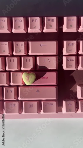 Candy heart on pink keyboard in sunlight