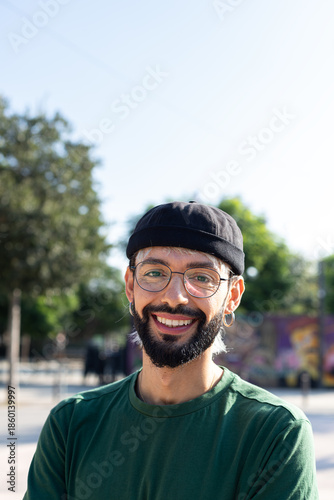 Vertical headshot portrait of happy young caucasian man outdoors looking at camera smiling.