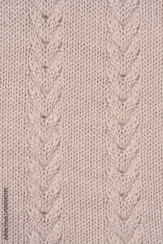 A close up full frame shot of a beige knitted wool fabric featuring two vertical cable patterns and a soft textured weave
