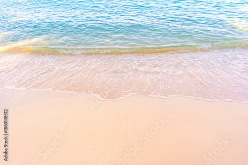 Soft blue ocean waves gently lapping onto a pristine tropical sandy beach