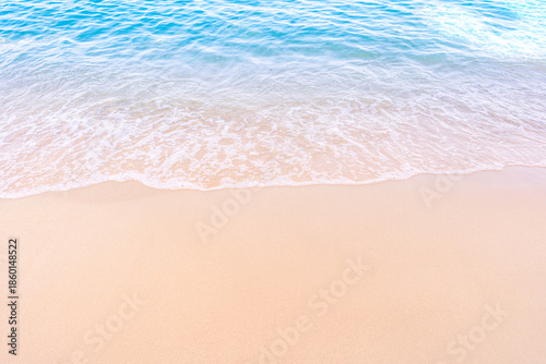 Soft blue ocean waves gently lapping onto a pristine tropical sandy beach