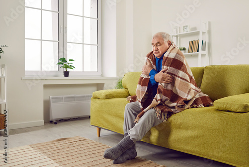 Fotografía Senior man shivering under blanket in winter