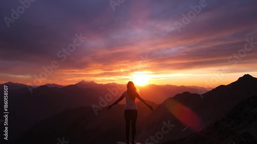 Woman with outstretched arms on mountain at sunset enjoying freedom.