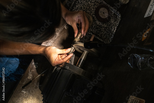 Photos Overhead view of artisan hands shaping a metal ring on a bench tool in a Bali, Indonesia jewelry workshop
