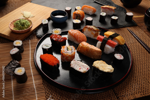 High-quality close-up of fresh assortment sushi rolls served on a dark plate, featuring vibrant colors, fresh fish, laid on slate board bamboo mat chopsticks