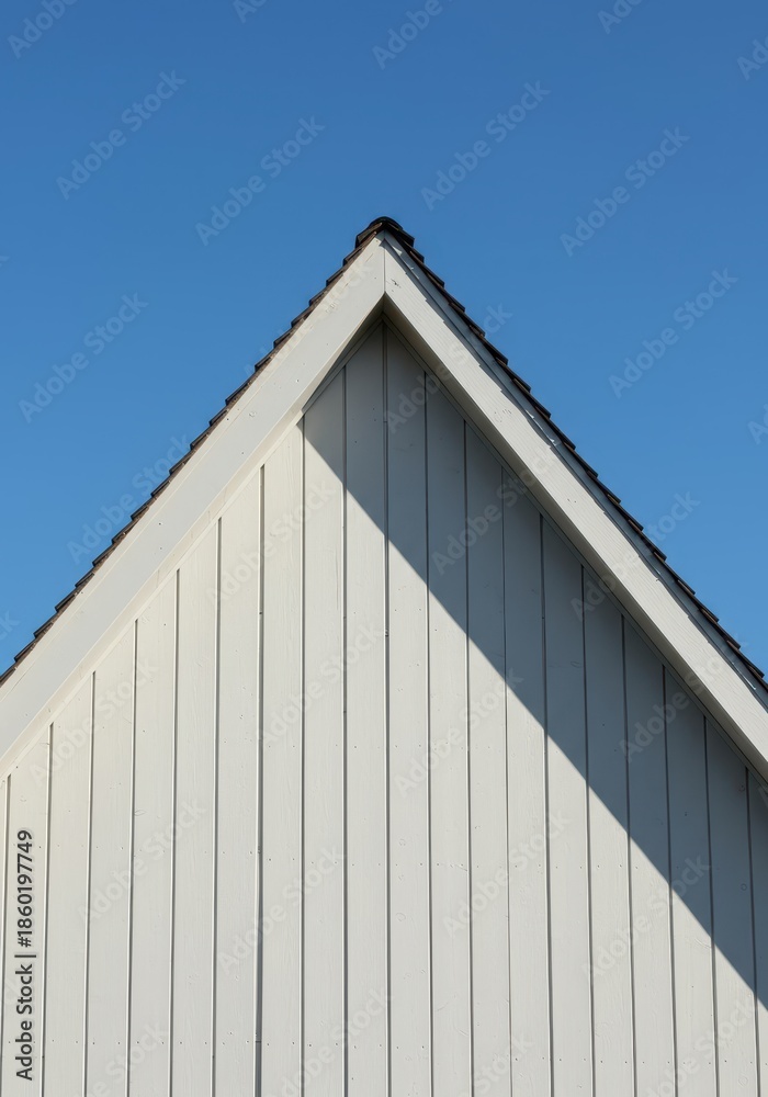 Fototapeta premium Architectural detail of a classic gable roof structure showing the triangular wall end and steep vertical siding against a clear sky, shelter, plank, beam