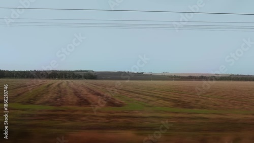 Power lines cross rural landscape under clear sky.