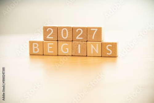 Wooden cube blocks 2027 begins background. Texts and numbers on wooden blocks with copy space. 2026 happy new year idea concept.