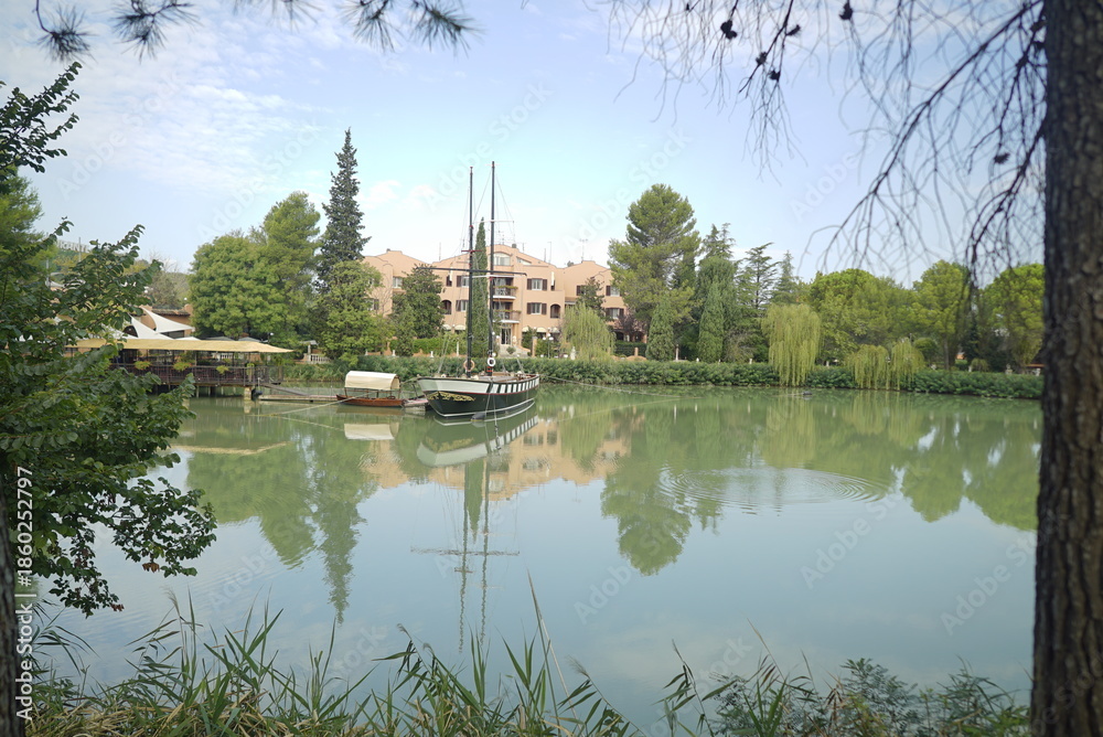 Obraz premium Lago di Monte Colombo con barca a vela e riflessi verdi – Rimini