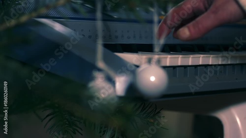 Christmas tree baubles with woman playing Christmas carols on piano organ 