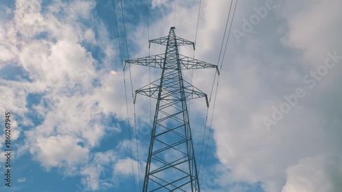 High Voltage Power Lines Rise Tall Against a Dramatic and Cloudy Sky Above The Landscape