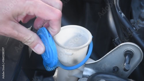 hand open blue cap of water tanker for car windshield wiper and filling clean fresh water to full