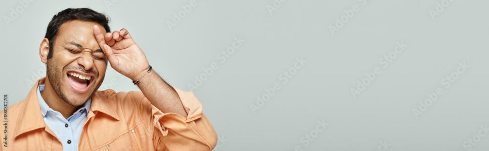 Fototapeta premium Joyful expression of a handsome Indian man enjoying a lighthearted moment indoors