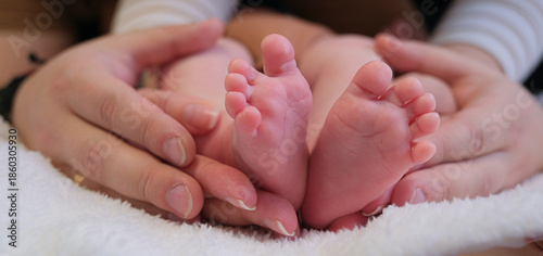 Фотография Parent hands gently cradling tiny newborn feet, conveying tender care, protectio