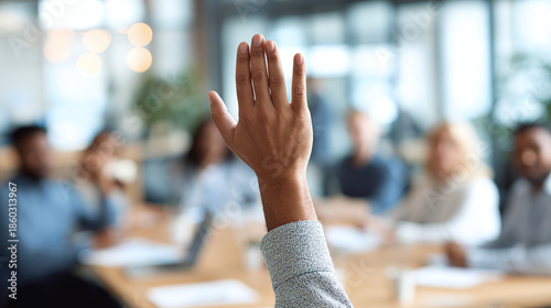 Close up of a person raising their hand in a meeting, asking a question, volunteering or suggesting an idea in business setting with other people.