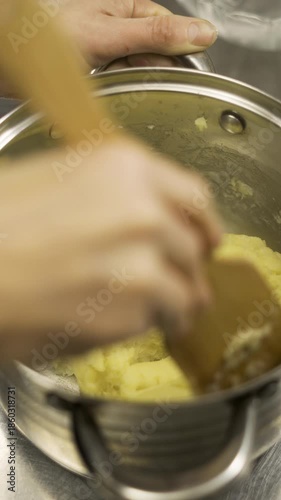 Stirring homemade pastry custard cream with wooden spatula in a saucepan.