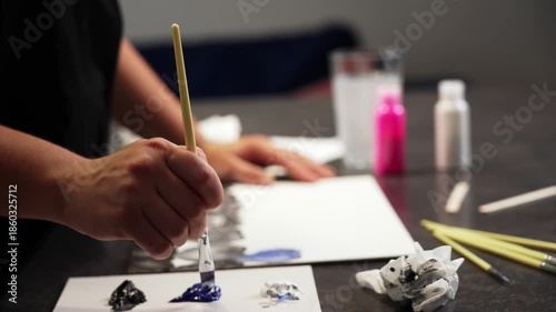 In a creative mess, a woman paints with a brush on a canvas. High quality 4k footage